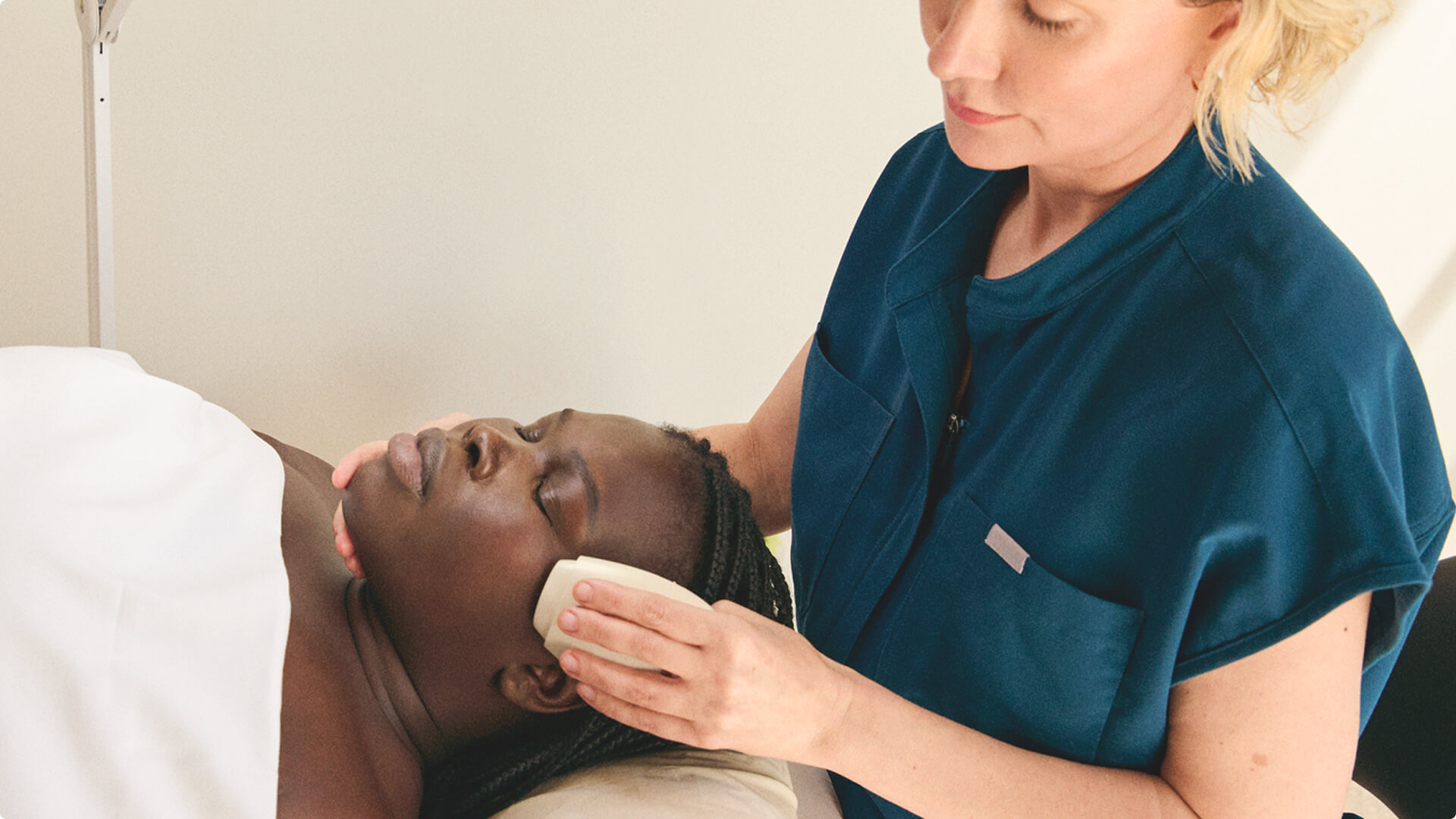 Woman laying down receiving facial treatment with electronic esthetician tool