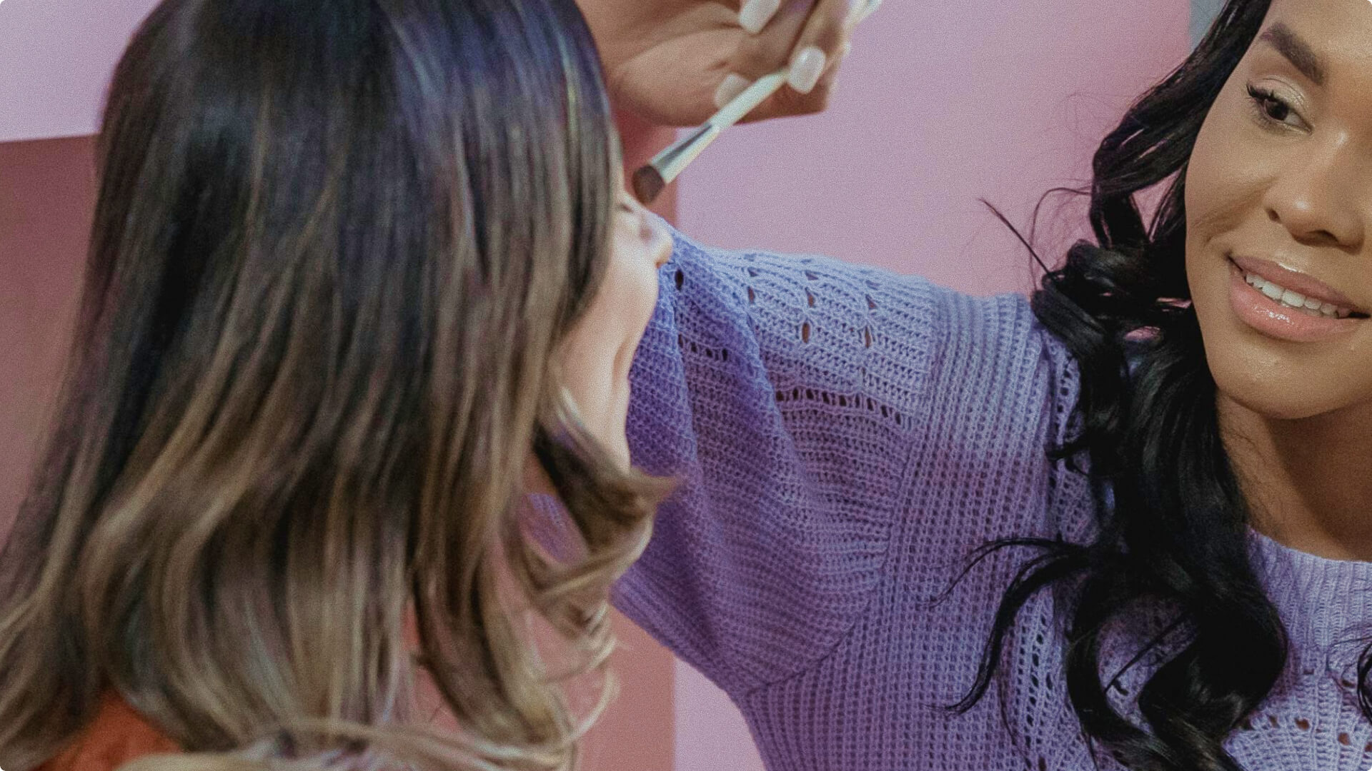 Makeup artist in purple sweater applying eye makeup to client