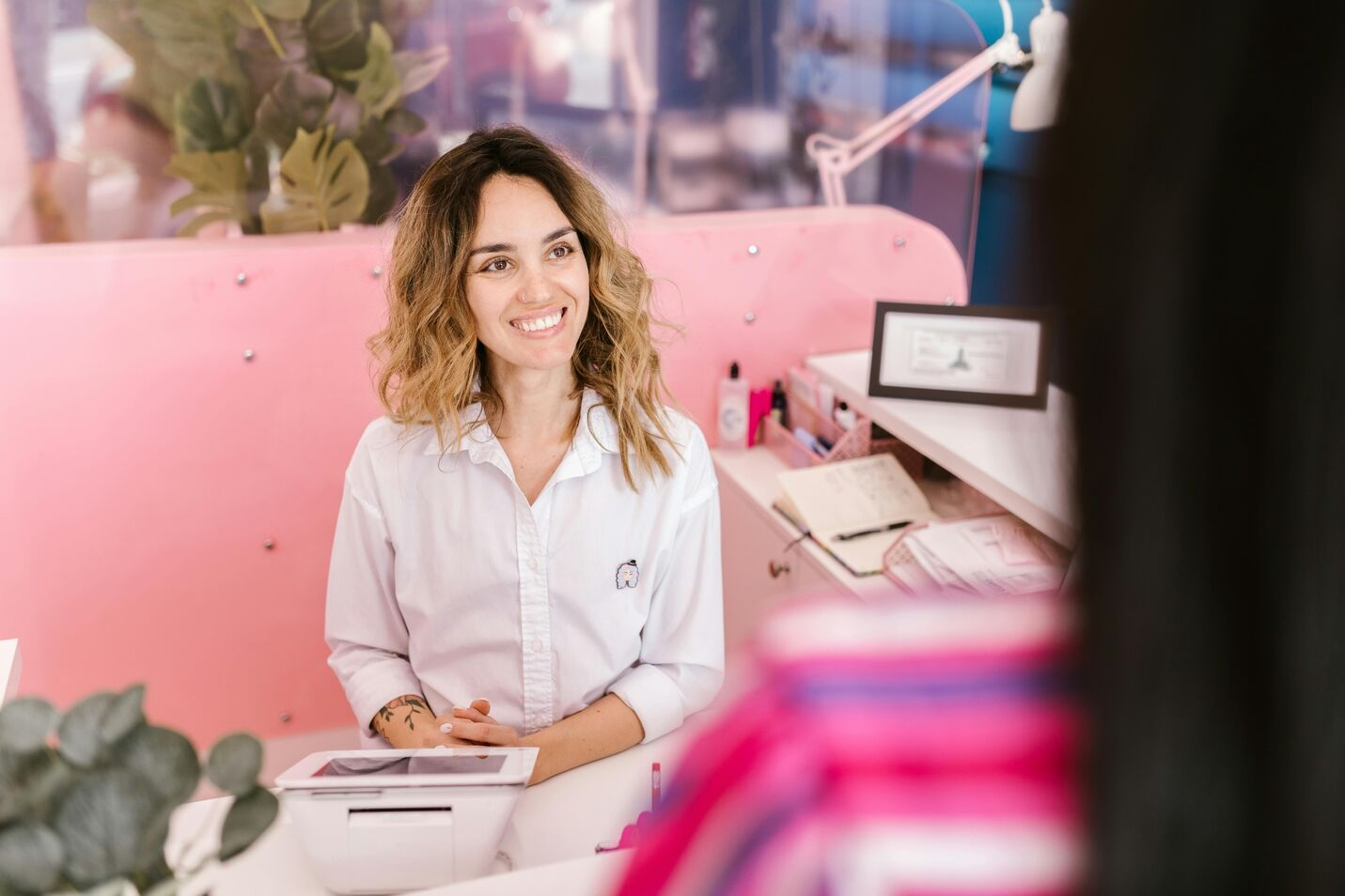 A salon receptionist in her desk welcoming a client